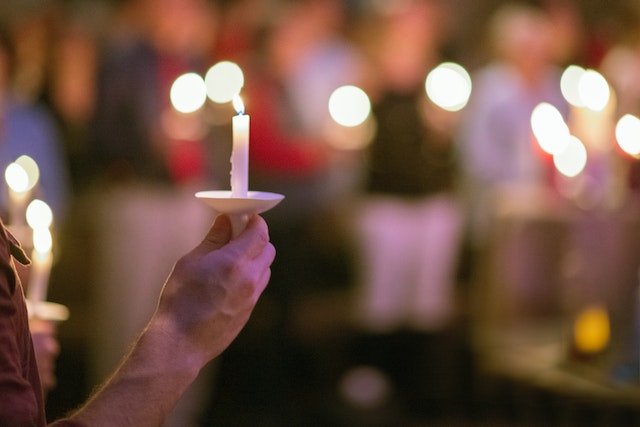 Dame hält Kerze bei individueller Bestattungsfeier
