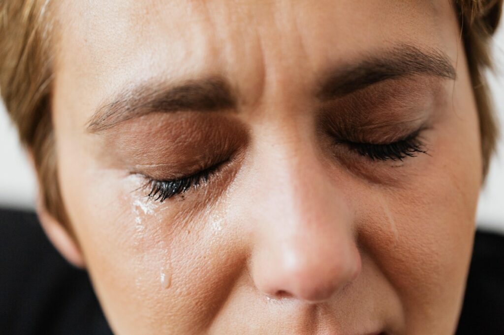 Wegen Sterbefall weinende Frau: Nahaufnahme vom Gesicht mit Tränen