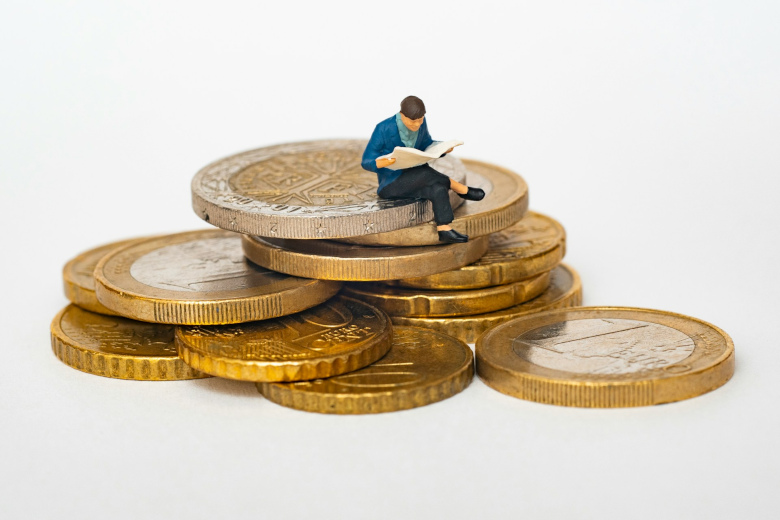 Kleiner Mann sitzt auf Münzen als Sinnbild für Finanzierung eines Vorsorgevertrags